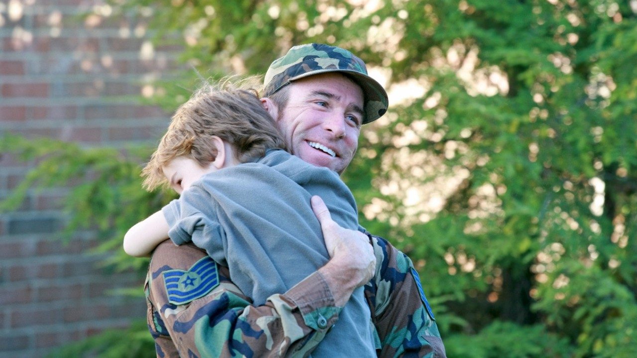 Father in uniform holding young son